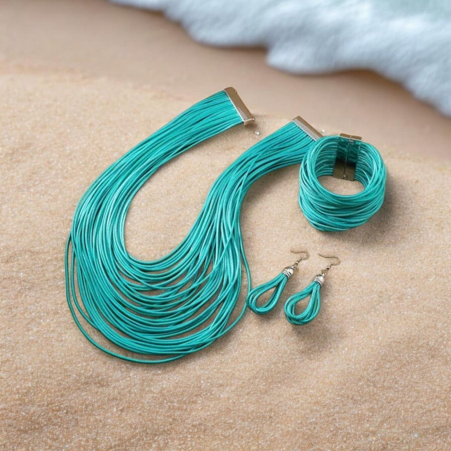 This artisanal 3-piece set includes a multi-layer braided necklace, bracelet, and matching earrings, all crafted from durable waxed thread in a vibrant turquoise hue.