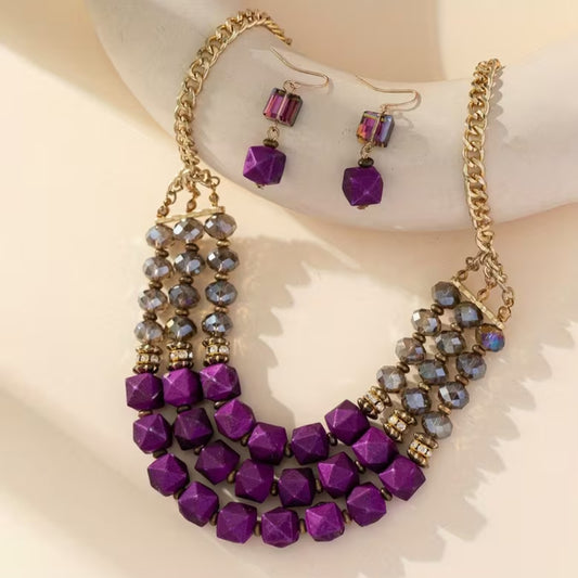 This 2‑piece bohemian style necklace set captures the free‑spirited charm of artisanal design while adding a touch of vintage allure. The necklace is crafted with layered strands that feature earthy textures and intricate detailing, giving it a relaxed yet sophisticated vibe. At the center, accents of purple color beads bring a vibrant pop that enhances the bohemian aesthetic. Complementing the necklace are matching vintage alloy earrings. 