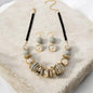 This chic 2-piece set captures vintage charm with a bold retro design. The necklace features alternating acrylic grey beads and shimmering gold beads, arranged in a balanced composition that radiates timeless elegance.