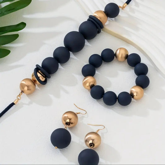 Elegant 3-piece set includes a multi-layer necklace, bracelet, and matching earrings, all crafted with matte acrylic beads. The design combines two harmonious tones — Ink blue and radiant gold — creating a warm, earthy palette with understated sophistication.