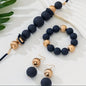 Elegant 3-piece set includes a multi-layer necklace, bracelet, and matching earrings, all crafted with matte acrylic beads. The design combines two harmonious tones — Ink blue and radiant gold — creating a warm, earthy palette with understated sophistication.