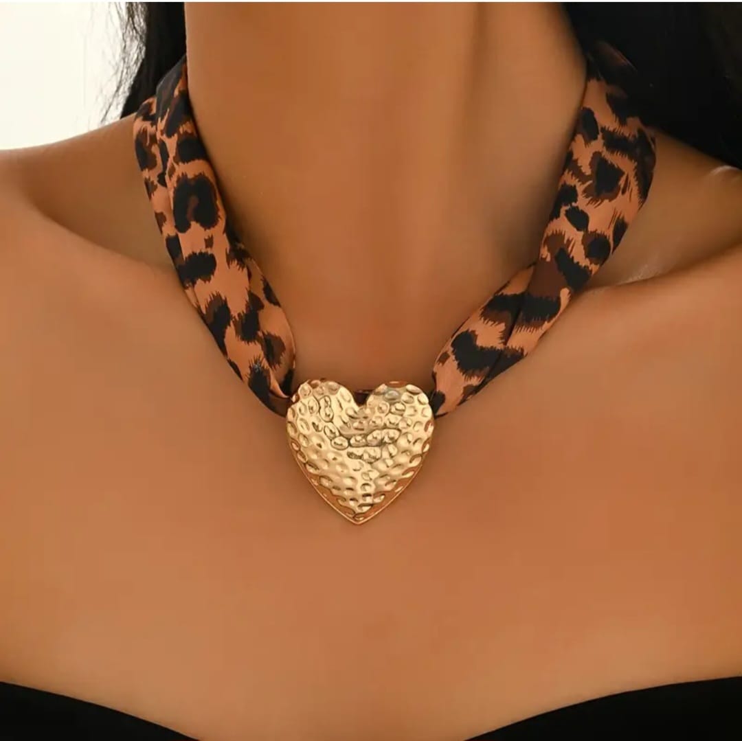 This bold and stylish necklace features a leopard print ribbon that exudes vintage charm and playful sophistication. At its center hangs a gold-plated hammered heart pendant, its textured surface catching the light with artisanal allure.