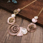 Designed in warm coffee shades accented by touches of soft pink, the necklace features intricately crafted alloy flowers paired with seashell elements that create a graceful, beach‑inspired look.