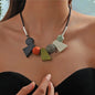 This striking necklace embodies a bohemian spirit with a tribal edge. Crafted in bold geometric shapes, it features earthy green tones that evoke nature and balance. The design blends angular symmetry with organic charm, creating a statement piece that feels both grounded and free-spirited.