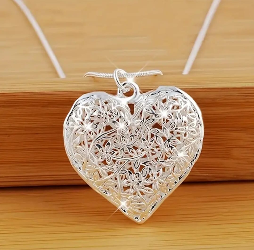 This elegant piece features a finely crafted sterling silver heart pendant delicately engraved with subtle detailing that adds depth and sentiment. Suspended from a sleek snake chain, the design balances modern sophistication with timeless romance